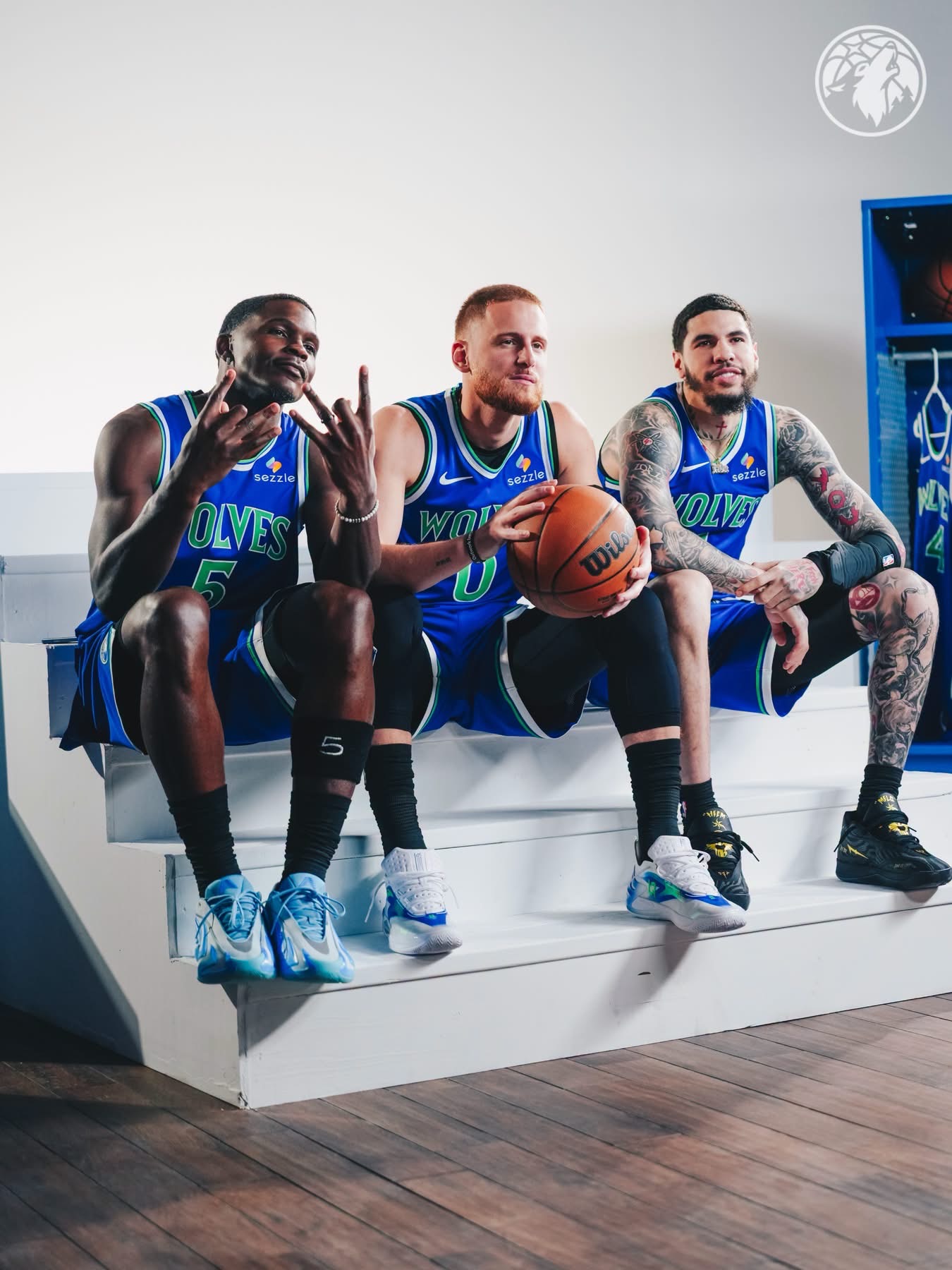 Anthony Edwards, Donte DiVincenzo and LaMelo Ball sitting on white steps in Wolves blue