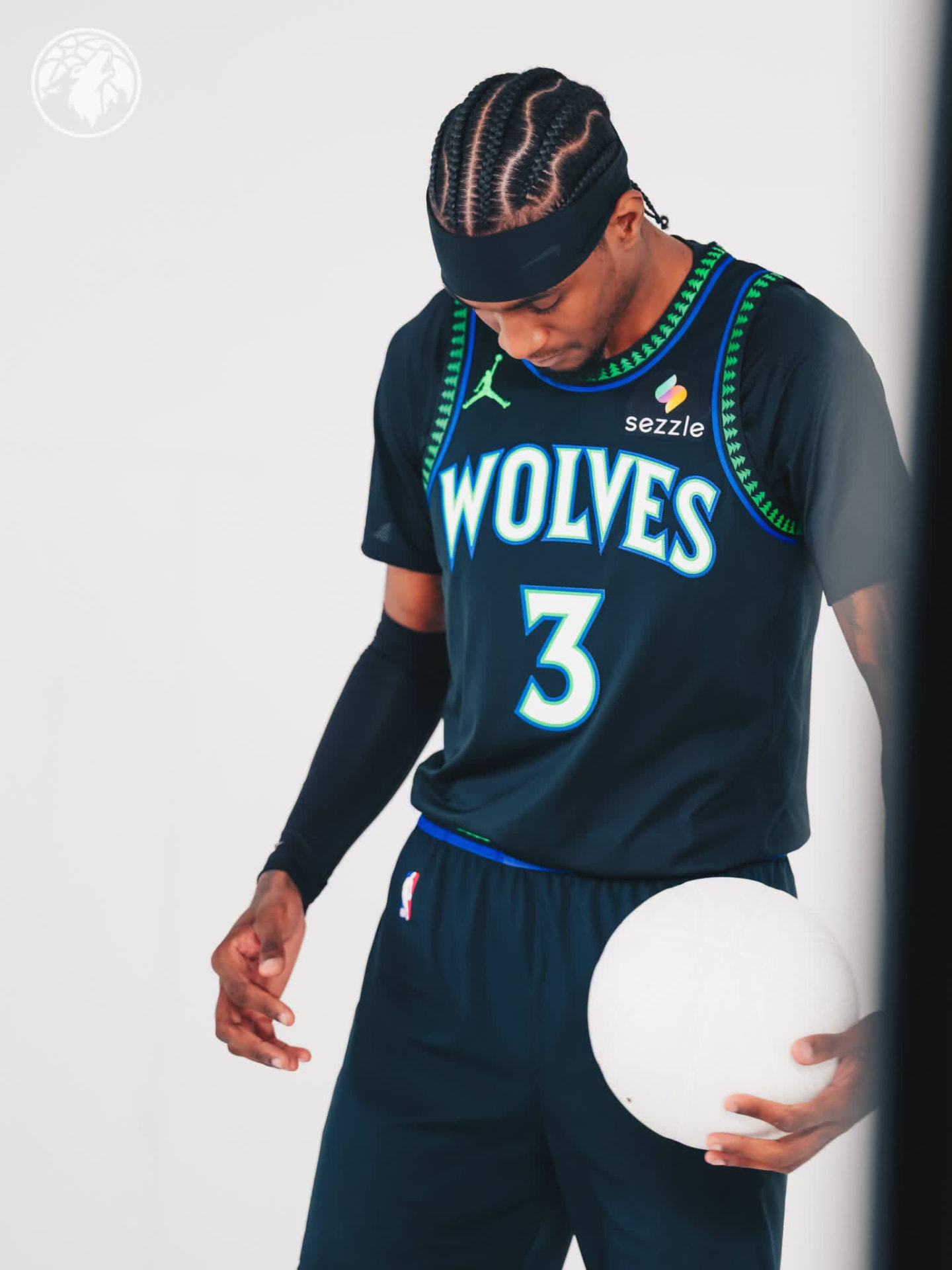 Jaden McDaniels looking down in the black Wolves #3 city edition jersey holding a white basketball