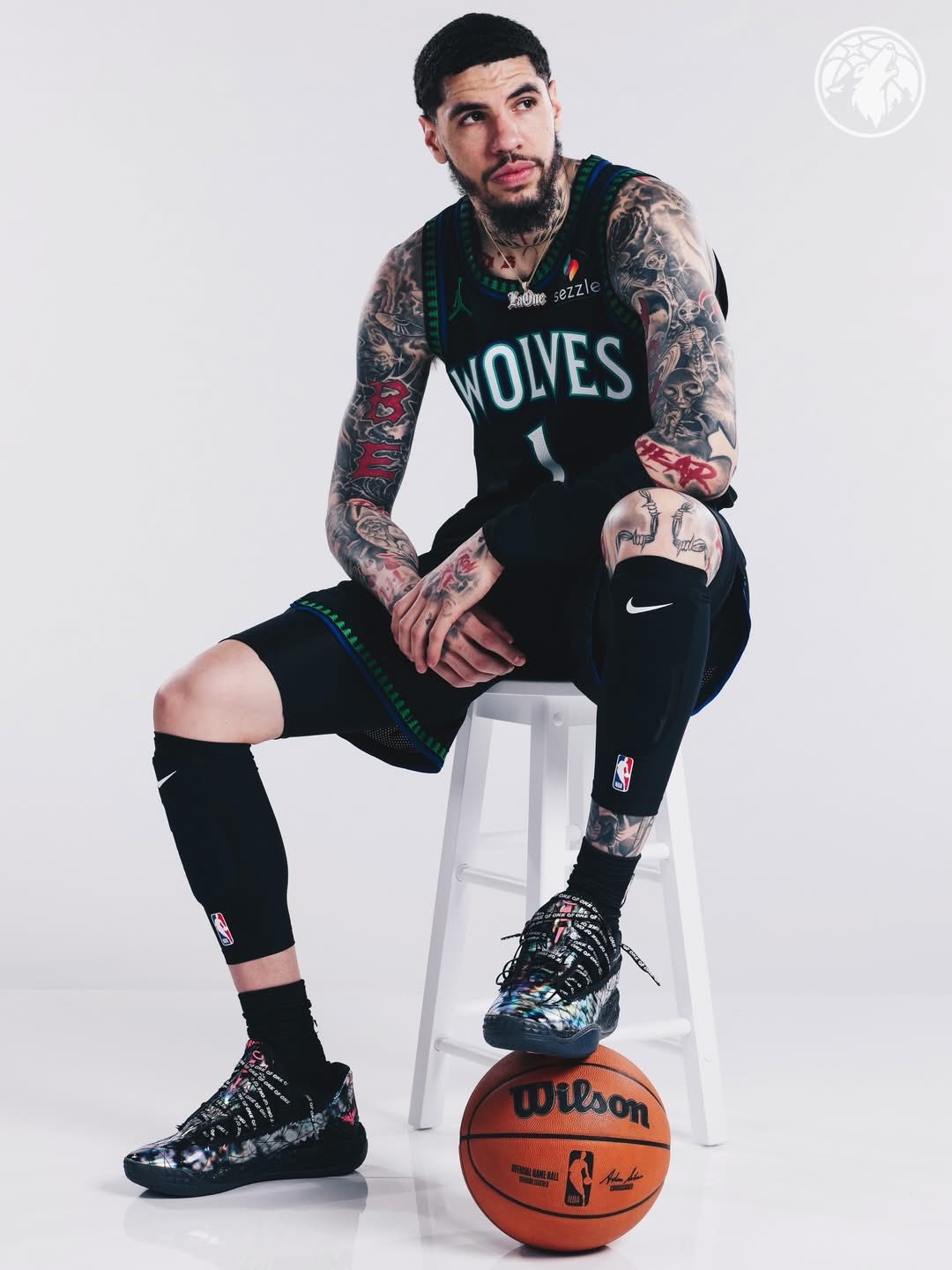 LaMelo Ball seated on a stool, foot resting on a basketball